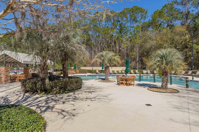 view of community featuring a pool, a patio, and fence