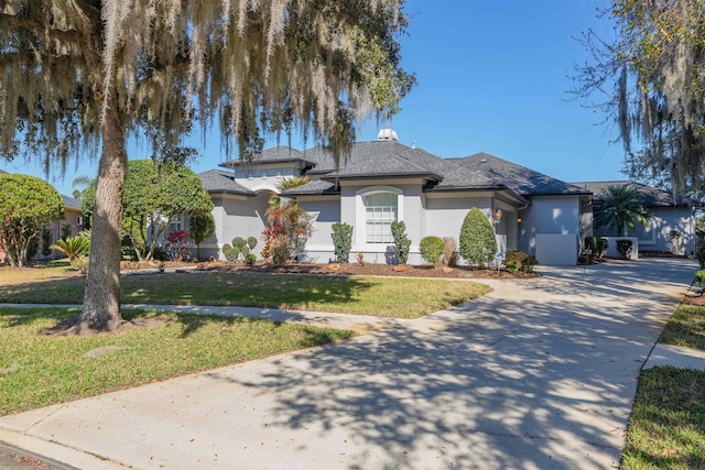 view of front of house featuring driveway, a front yard, and stucco siding