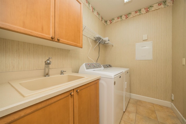 washroom featuring cabinet space, light tile patterned floors, baseboards, washer and clothes dryer, and a sink