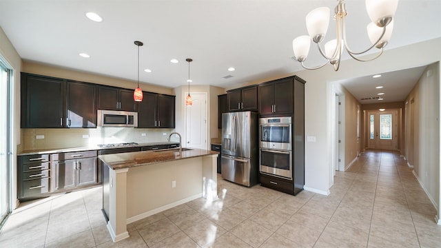 kitchen featuring stainless steel appliances, a chandelier, pendant lighting, decorative backsplash, and a center island with sink