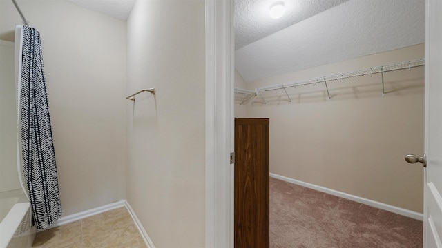 walk in closet with lofted ceiling and light carpet