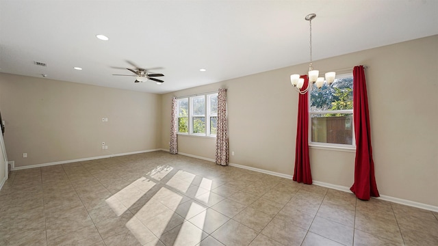 tiled spare room featuring ceiling fan with notable chandelier