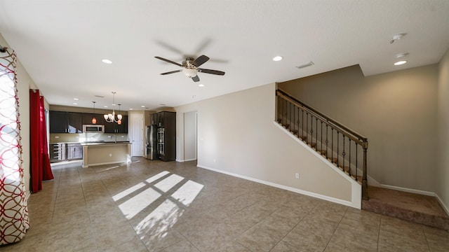 unfurnished living room featuring sink, dark tile patterned flooring, and ceiling fan with notable chandelier