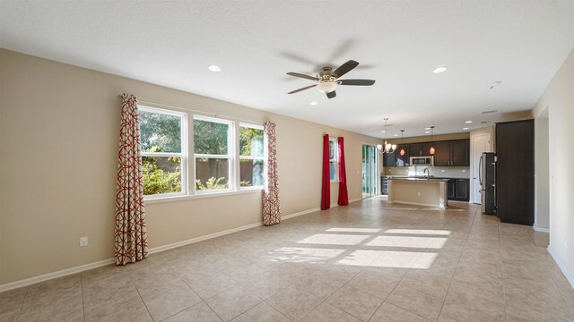 unfurnished living room featuring ceiling fan with notable chandelier and light tile patterned floors