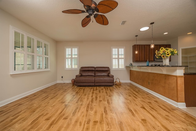 interior space featuring ceiling fan, light wood-type flooring, and a textured ceiling