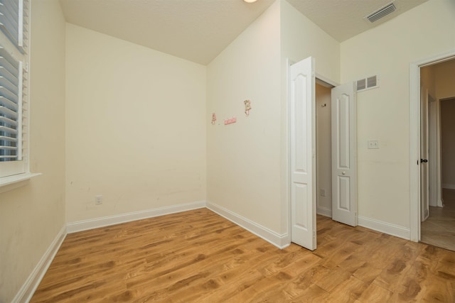 spare room featuring a textured ceiling and light wood-type flooring