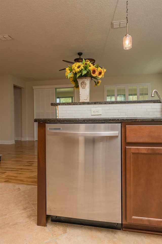 kitchen with stainless steel dishwasher, dark stone countertops, pendant lighting, a textured ceiling, and light wood-type flooring