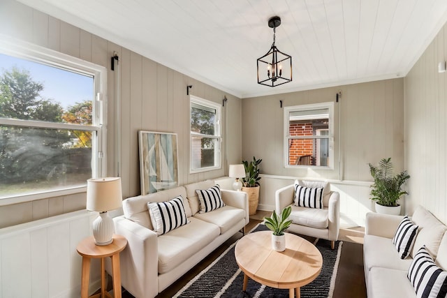 living room featuring a chandelier, wooden walls, and crown molding