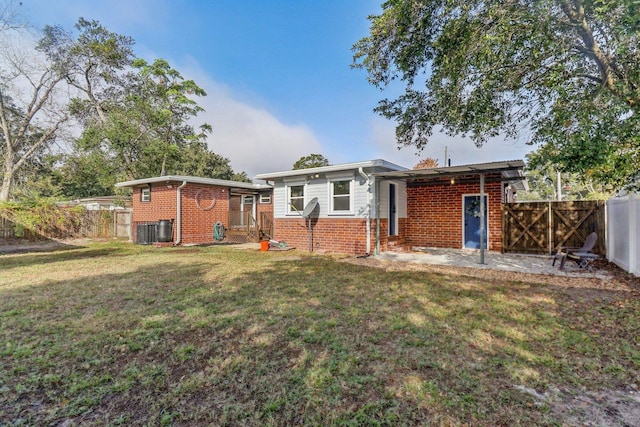 rear view of property featuring central AC and a lawn