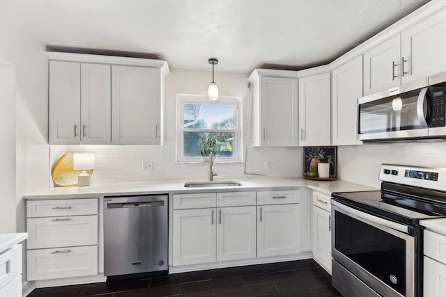 kitchen featuring white cabinetry, sink, tasteful backsplash, decorative light fixtures, and appliances with stainless steel finishes