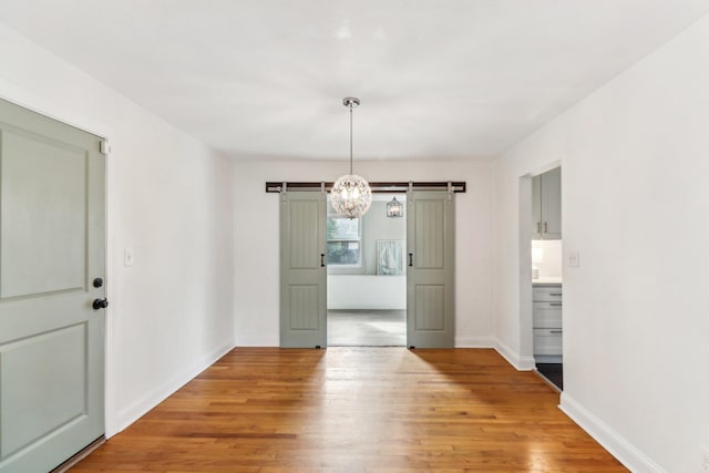 unfurnished dining area featuring a barn door and hardwood / wood-style flooring