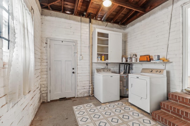 clothes washing area with brick wall and washing machine and clothes dryer