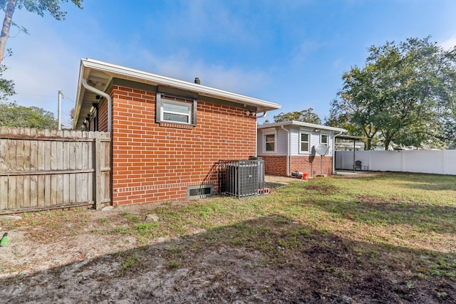 back of house with central air condition unit and a lawn