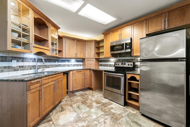 kitchen with decorative backsplash, appliances with stainless steel finishes, sink, and dark stone countertops