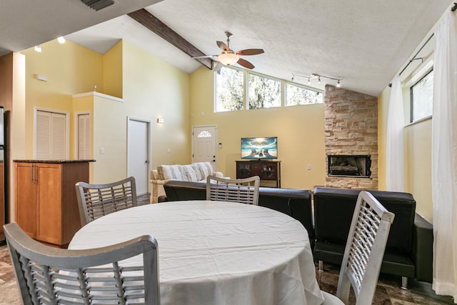 dining area with a wealth of natural light, ceiling fan, a fireplace, and high vaulted ceiling