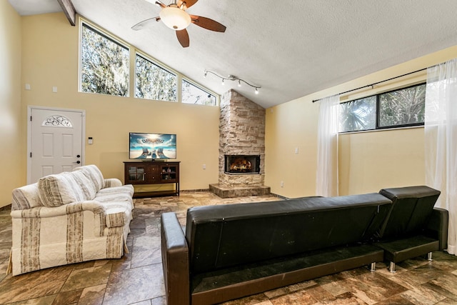 living room with a stone fireplace, ceiling fan, high vaulted ceiling, and a textured ceiling