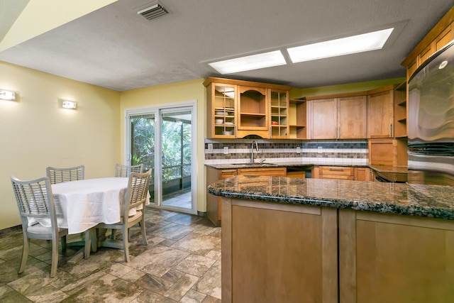 kitchen with tasteful backsplash, dark stone countertops, and sink