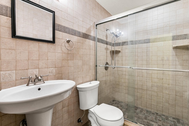 bathroom with a shower with door, toilet, and tile walls