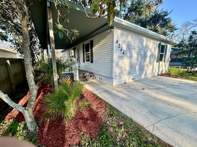 view of property exterior with covered porch, crawl space, and fence