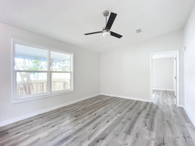 unfurnished room with a textured ceiling, light wood-type flooring, a ceiling fan, and baseboards