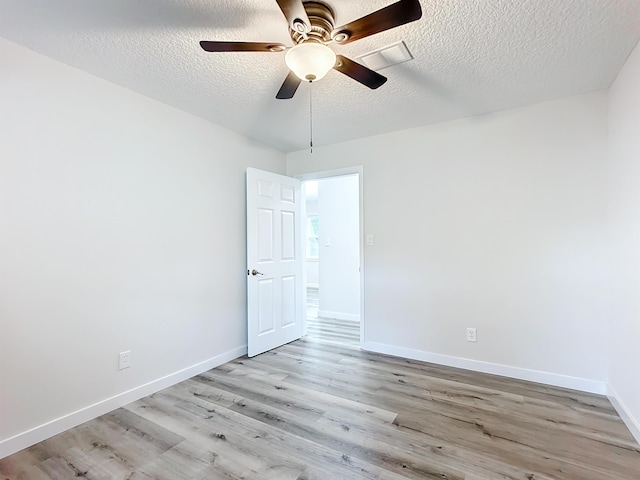 unfurnished room featuring light wood-style floors, a ceiling fan, baseboards, and a textured ceiling