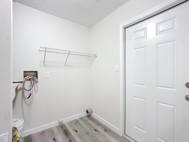 laundry area with hookup for a washing machine, light wood-style floors, a textured ceiling, laundry area, and baseboards