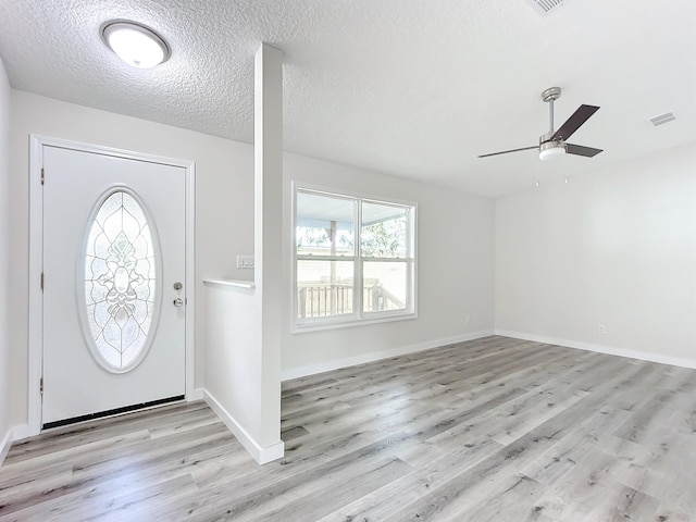 foyer featuring visible vents, light wood-style flooring, a ceiling fan, a textured ceiling, and baseboards