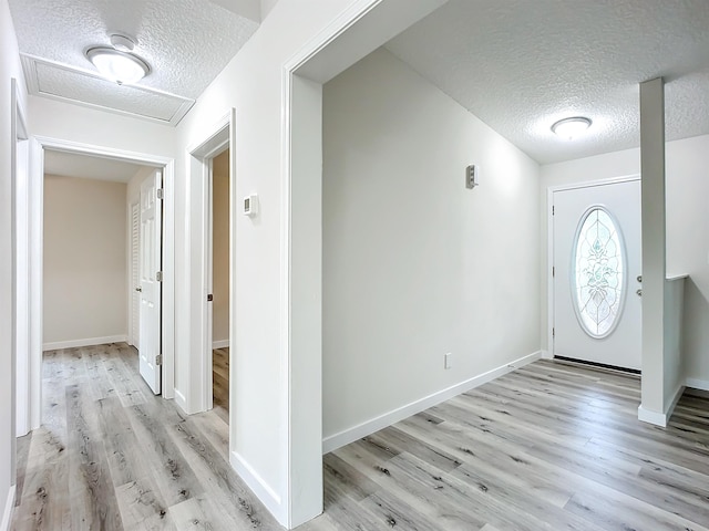 entrance foyer with light wood-style floors, baseboards, and a textured ceiling