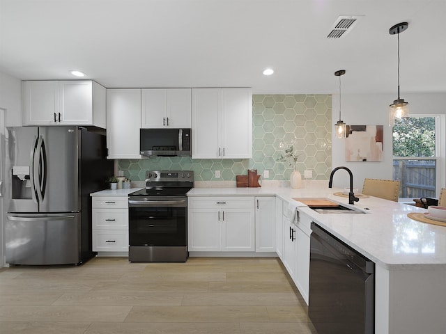 kitchen with appliances with stainless steel finishes, kitchen peninsula, white cabinets, and decorative light fixtures