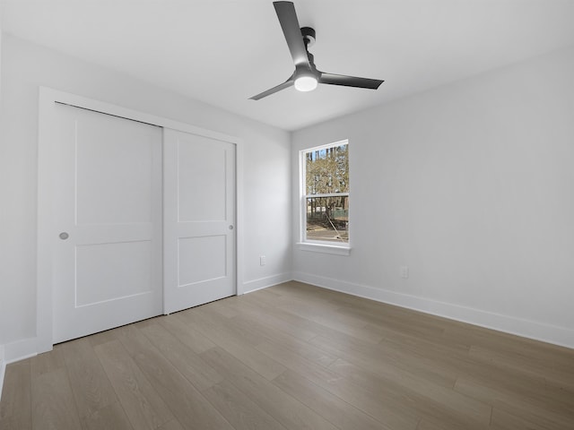 unfurnished bedroom with ceiling fan, a closet, and light wood-type flooring