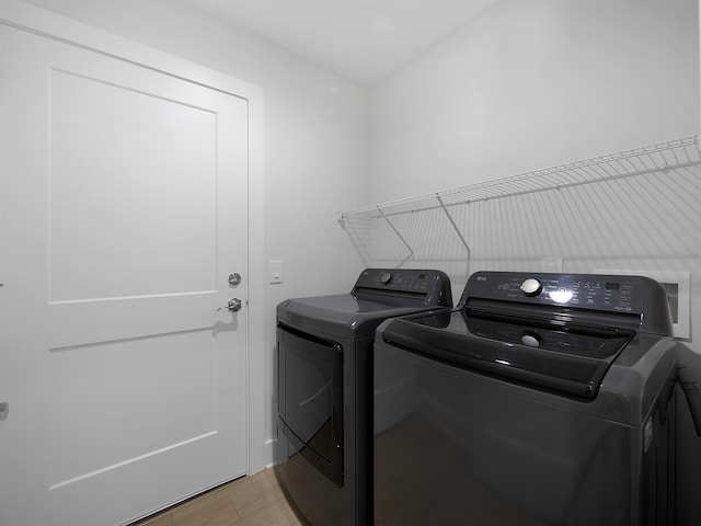 clothes washing area with separate washer and dryer and light hardwood / wood-style flooring