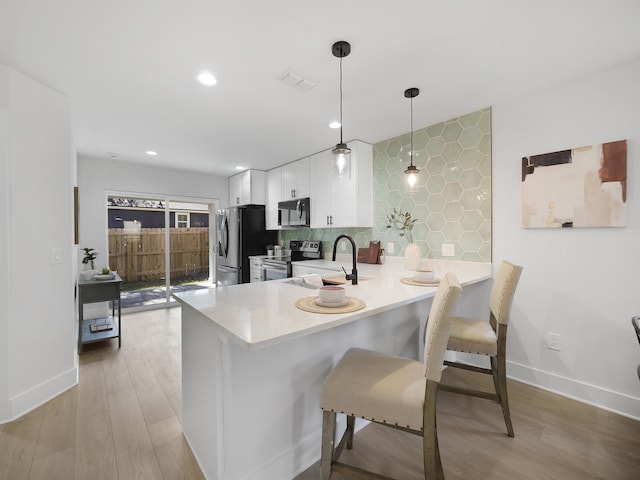 kitchen with white cabinetry, sink, hanging light fixtures, kitchen peninsula, and stainless steel appliances