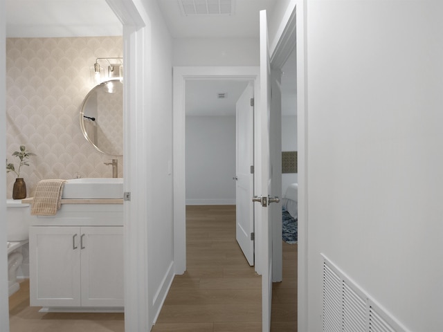 hallway featuring sink and light hardwood / wood-style flooring