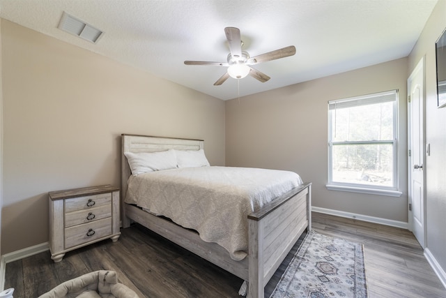 bedroom with a textured ceiling, ceiling fan, and dark wood-type flooring