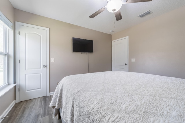 bedroom with multiple windows, wood-type flooring, and ceiling fan