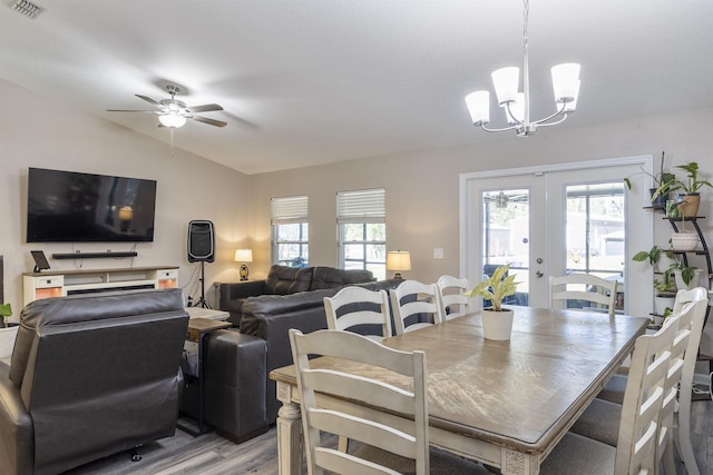 dining area with hardwood / wood-style flooring, ceiling fan with notable chandelier, vaulted ceiling, and french doors