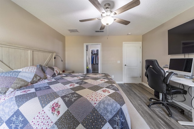 bedroom with a textured ceiling, ceiling fan, a spacious closet, hardwood / wood-style floors, and a closet