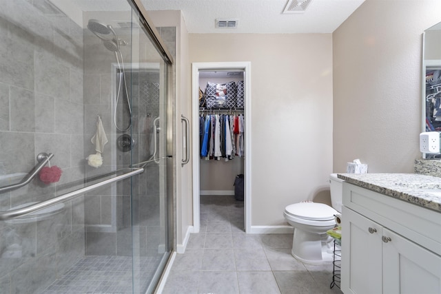 bathroom with vanity, tile patterned flooring, toilet, a textured ceiling, and an enclosed shower