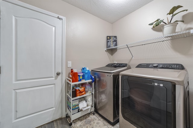 laundry area featuring a textured ceiling, light hardwood / wood-style flooring, and washing machine and dryer