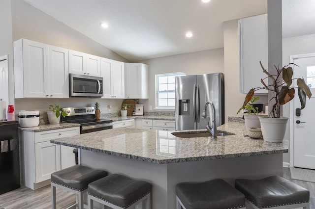 kitchen featuring a kitchen bar, stainless steel appliances, and white cabinets