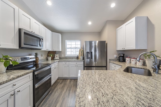 kitchen with light stone counters, sink, white cabinetry, and stainless steel appliances