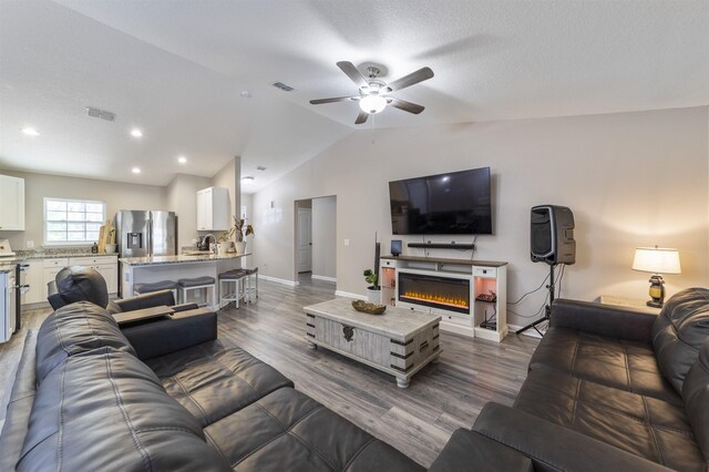 living room featuring dark hardwood / wood-style floors, ceiling fan, lofted ceiling, and a textured ceiling