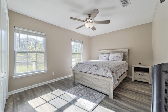 bedroom with ceiling fan, dark hardwood / wood-style flooring, and multiple windows