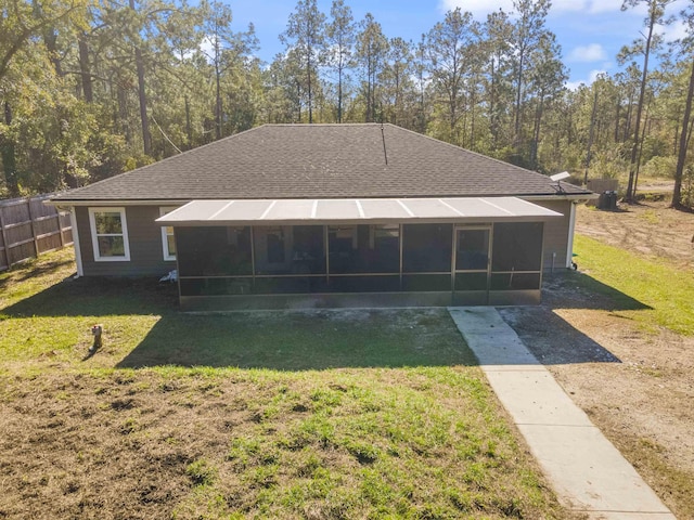 rear view of house featuring a lawn and a sunroom