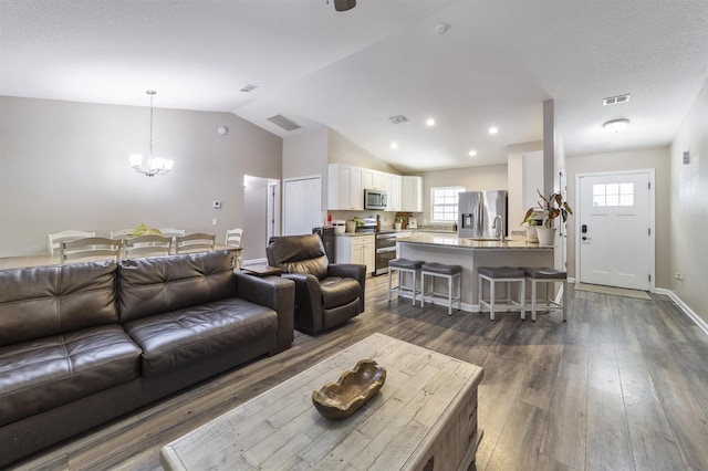 living room with dark hardwood / wood-style flooring, lofted ceiling, and a chandelier