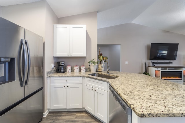 kitchen featuring white cabinetry, sink, stainless steel appliances, light stone counters, and vaulted ceiling