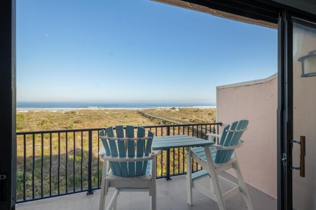 balcony with a water view and a view of the beach