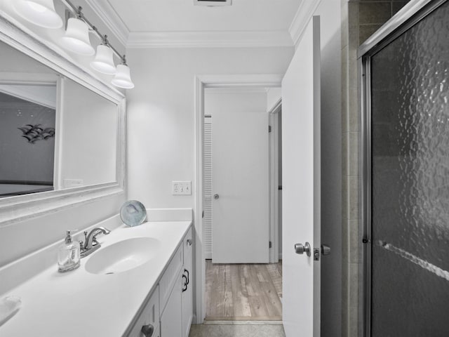 bathroom featuring hardwood / wood-style flooring, crown molding, an enclosed shower, and vanity