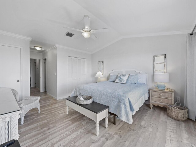 bedroom featuring ceiling fan, ornamental molding, vaulted ceiling, a closet, and light wood-type flooring