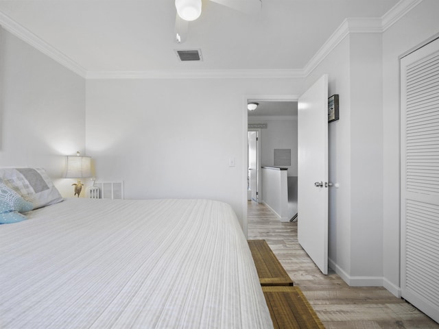 bedroom with ornamental molding, light hardwood / wood-style floors, ceiling fan, and a closet